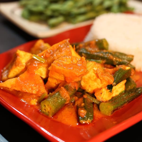 Burmese curry with tofu and okra in a rich orange sauce, served with white rice.